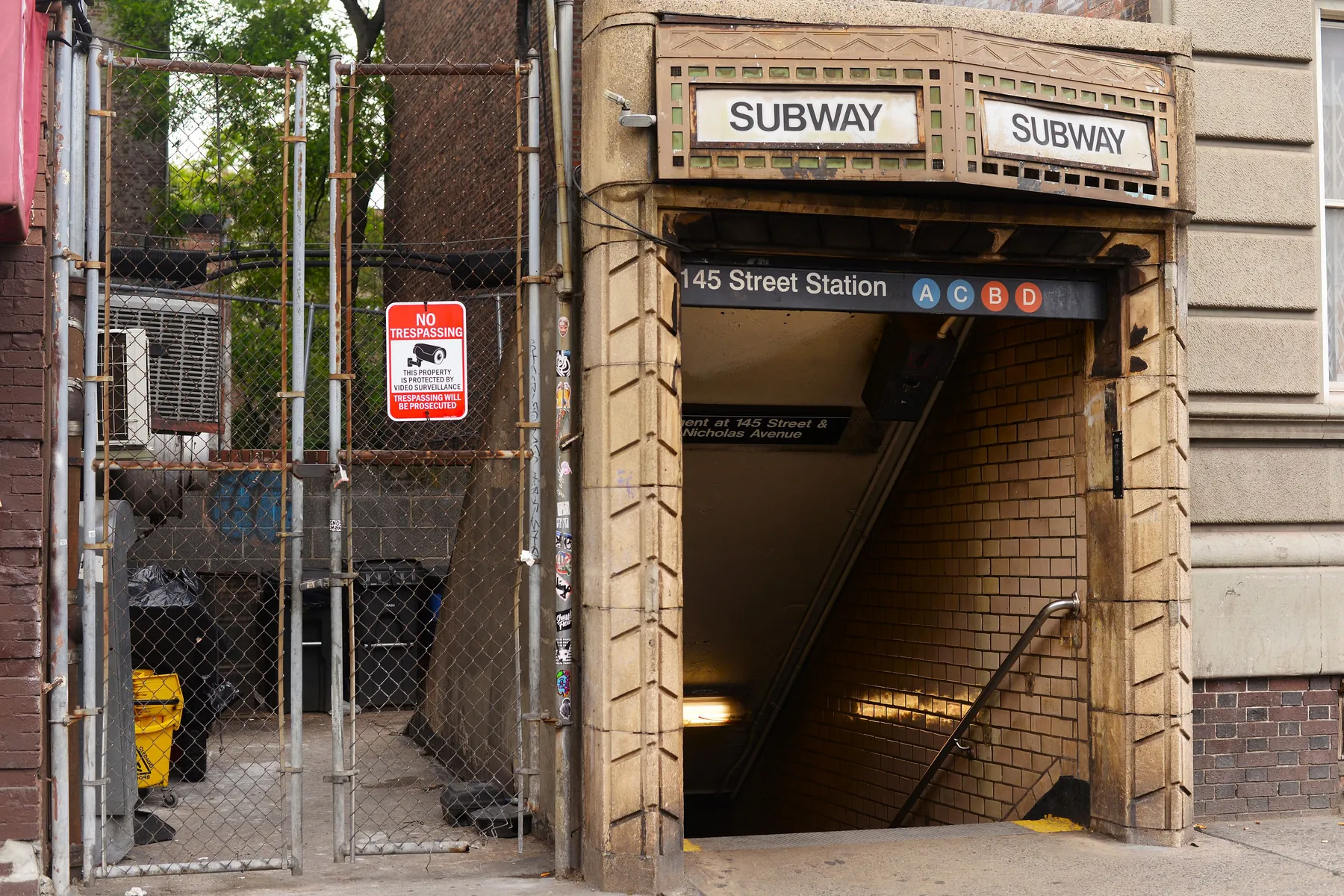 Kamenný vstup do metra označený 145 Street Station se značkami linek A, C, B a D na ceduli